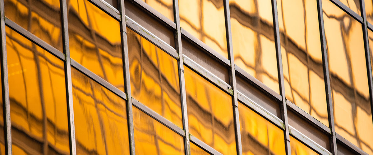 muro cortina naranja con reflejos de otro edificio